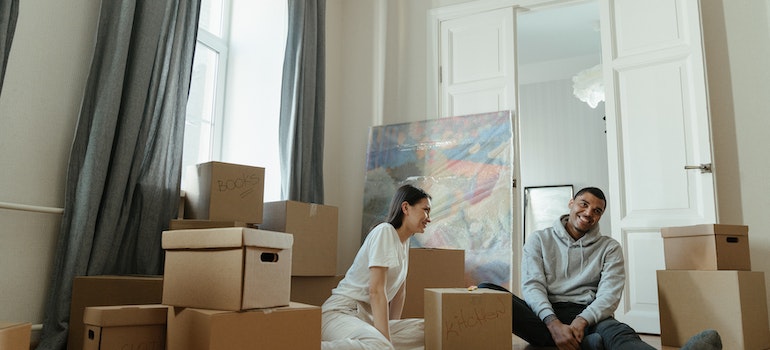 happy couple sitting between boxes