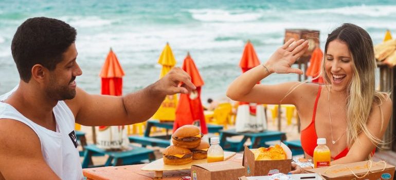 a couple eating burgers at the beach