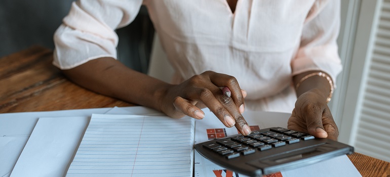 a woman using a calculator to calculate the cost of moving from Palm Bay to Hialeah