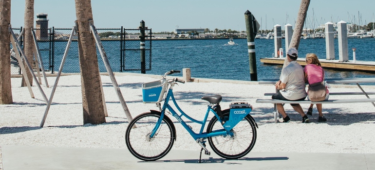 A couple sits on a bench and watches the sea bay, bicycles in the foreground