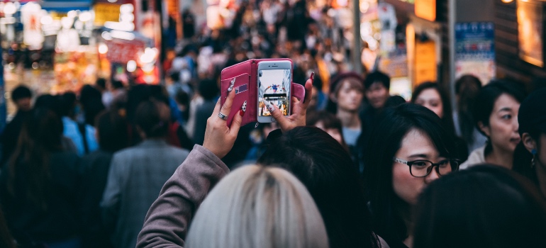 A woman taking a photo in a crowded area after moving from Riverview to Miami