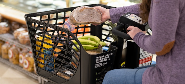 Woman in Walmart putting bread in her shopping trolly 