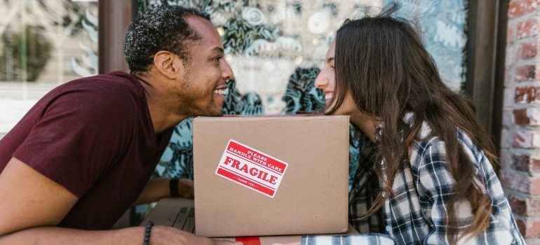 A couple smiling and holding a box