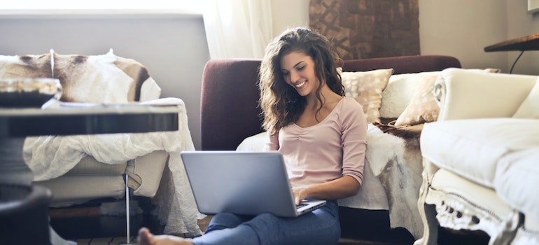 A girl smiling and using her laptop to find some of the best local movers Beach Gardens