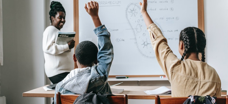 Pupils in the class raising hands. 