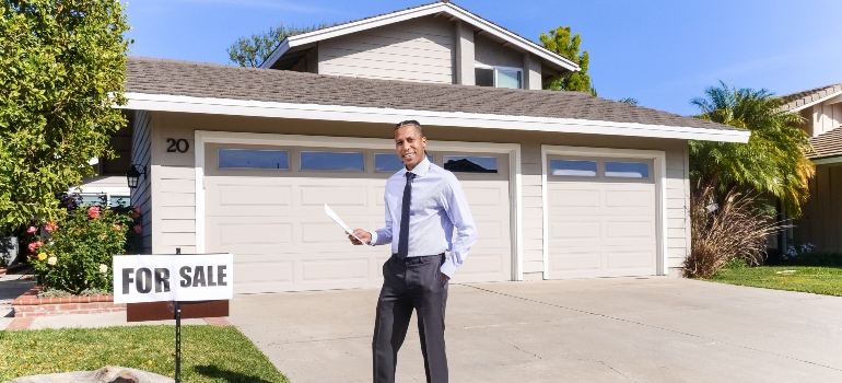 A real estate agent standing in front of a house for sale