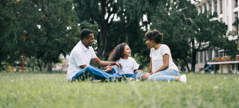 A family smiling while sitting on the grass