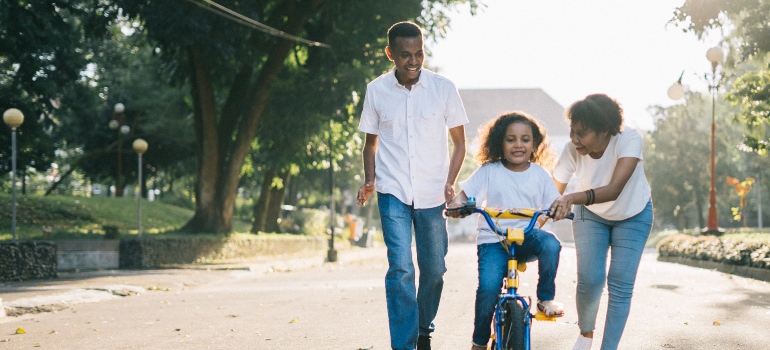 Parents helping their daughter ride a bike after moving from Gainesville to Miami