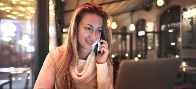 Woman in a cafe smiling while talking on the phone with local movers Pensacola offers