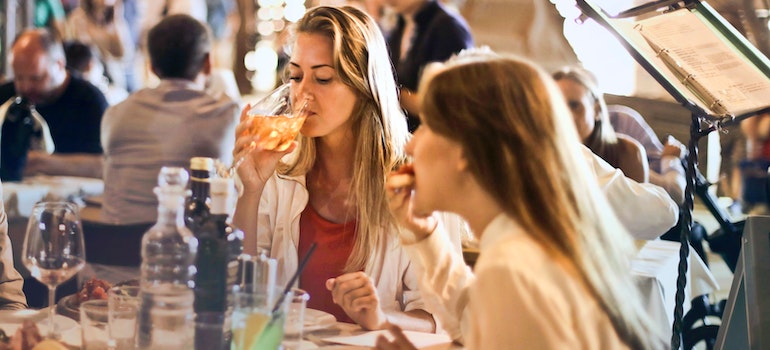 Two women sitting in an open restaurant drinking wine and eating Cuban food