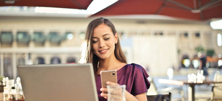 Woman smiling while looking down at her phone trying to find commercial movers Beach Gardens