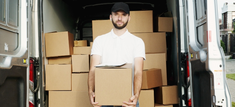 A man in a white shirt smiling while holding a moving box