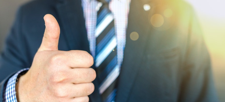 A man in a blue suit holding a thumbs up