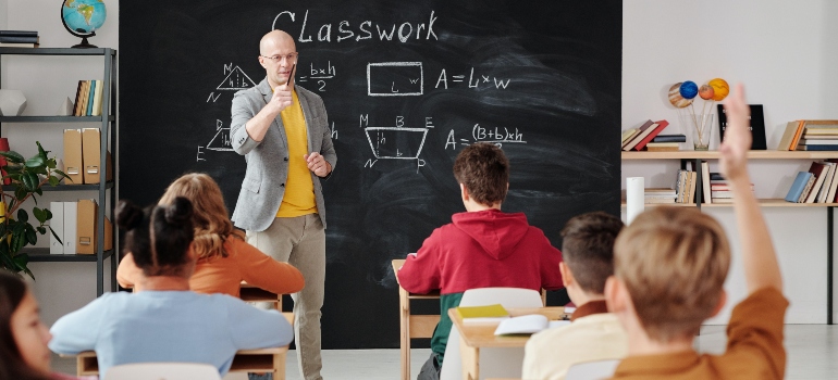 A kid raising his hand in a classroom