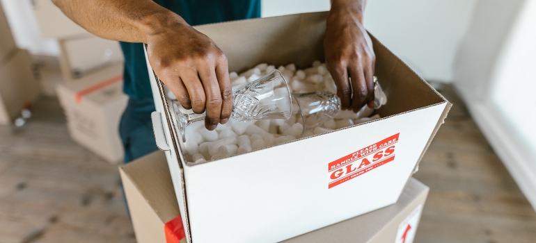 A mover packing glass in a moving box