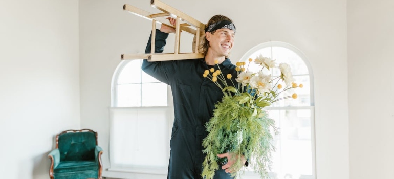 A man holding flowers and a chair