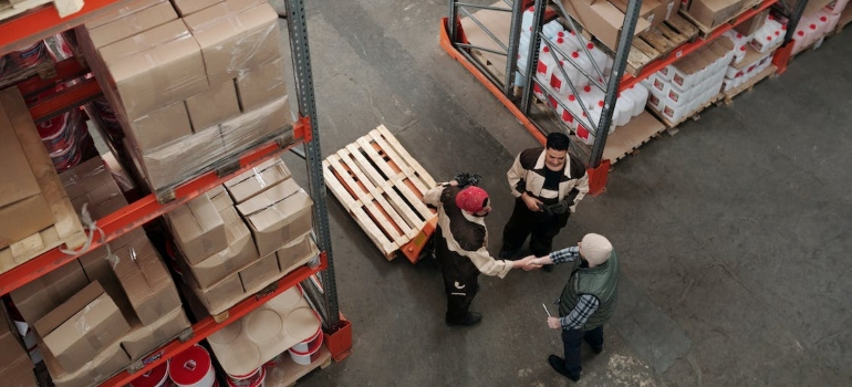 three men talking to each other in a warehouse