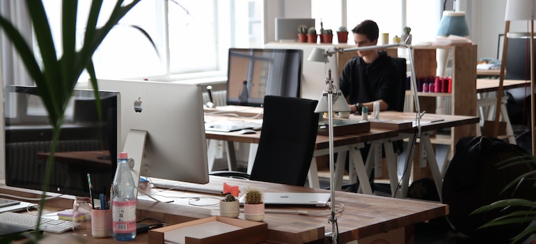 A man in an office working, surrounded by computers