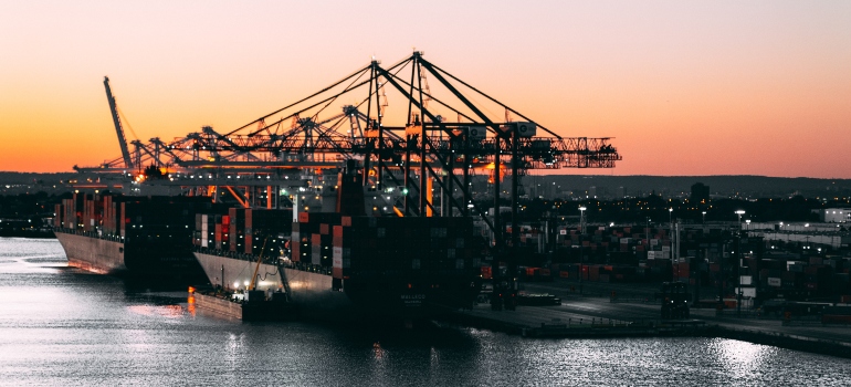 A port in Florida with cranes and two cargo ships at sunset