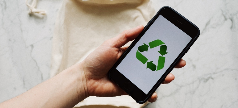 A person holding a phone with the eco-friendly sign as its background