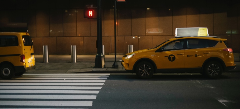 A yellow taxi on the road at night