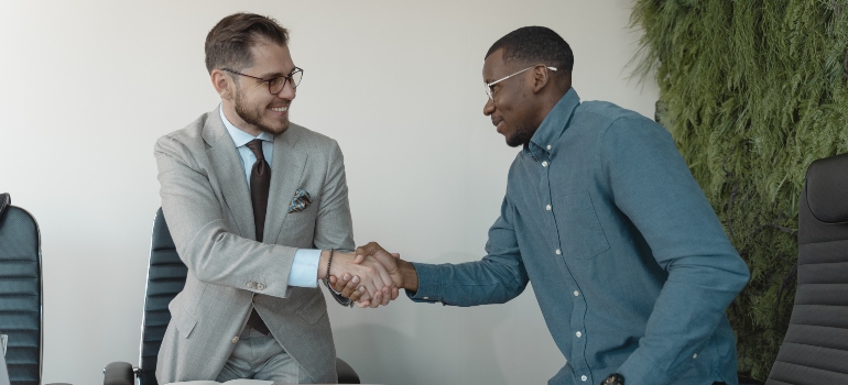 Two men in formal wear shacking hands in an office