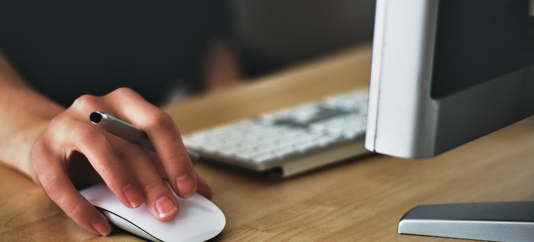 a person using a white wireless mouse to browse something on her mac