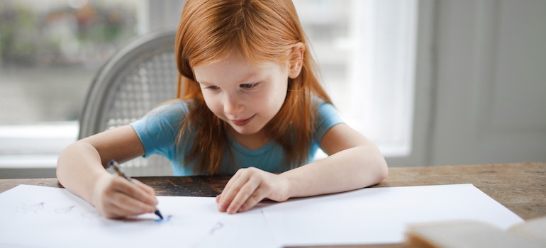 little ginger girl coloring on a piece of paper