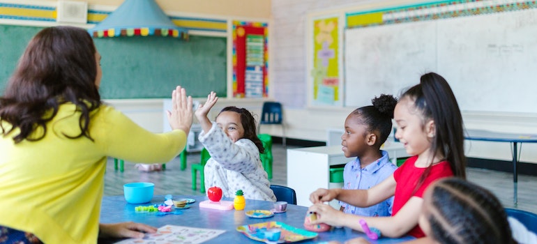 Kids playing with a teacher in a small classroom