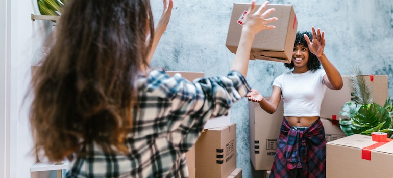 Two women passing a moving box to one another