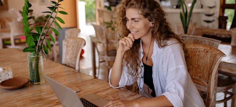 A woman with long wavy hair sitting in a caffe on a yoom call talking about moving from Clearwater to Miami for a job