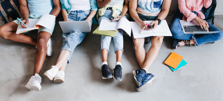 Students sitting on a white floor with books in their laps