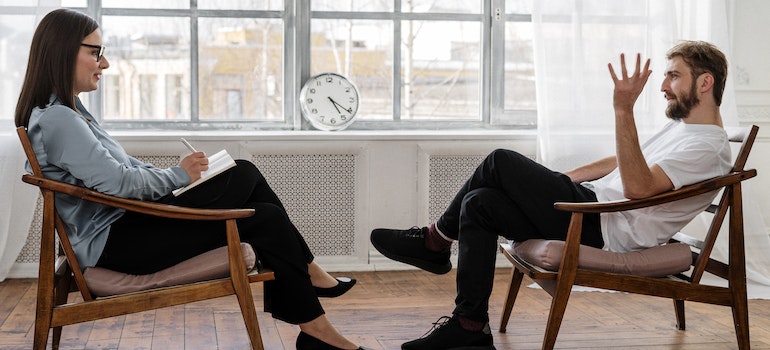 A man sitting on a low chair with his therapist