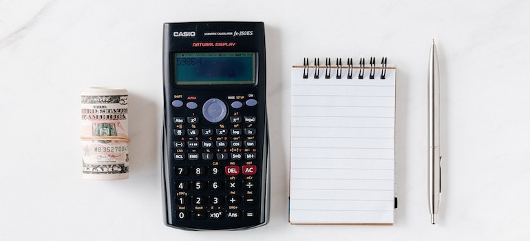a calculator, money and a notepad on the table
