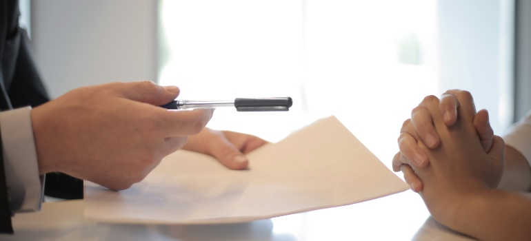 a businessman giving a contract to a woman to sign after moving from Miami to NYC