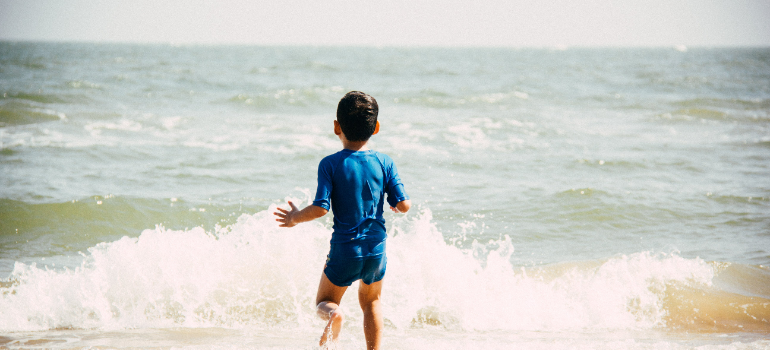 a boy happily running to the sea after moving from Pensacola to Miami