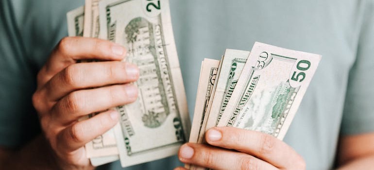 A person counting money and calculating the financial changes of rural living after moving