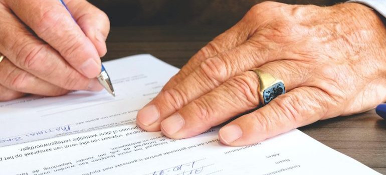 An elderly person signing a contract