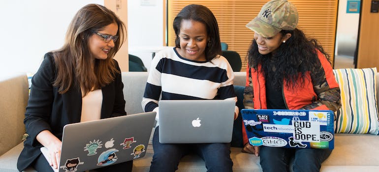 three young women looking at lap tops