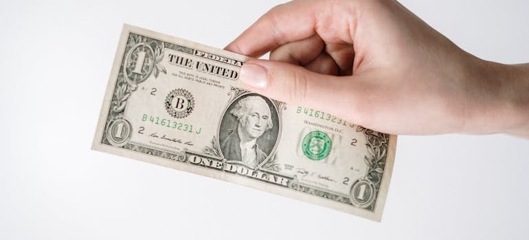 a hand holding a dollar bill