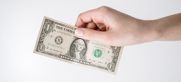 a hand holding a dollar bill