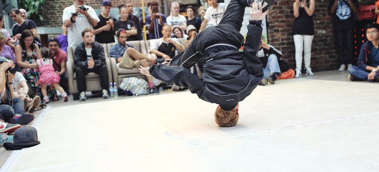 A man is doing a spin on the top head while dancing a breakdance at one of the popular festivals in South Florida.