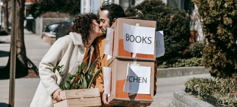 A couple kissing while carrying moving boxes