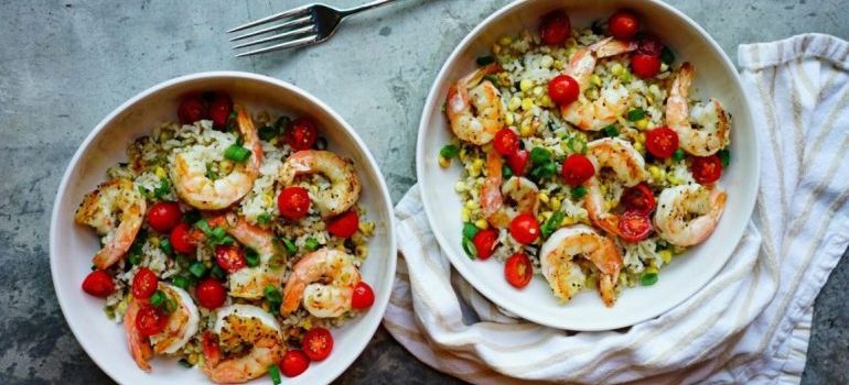 Two bowls of shrimp with rice and vegetables
