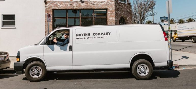 a man sitting in a white van with sign moving company you can hire to protect yourself and your belongings on moving day