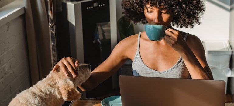 A woman petting a dog and drinking tea