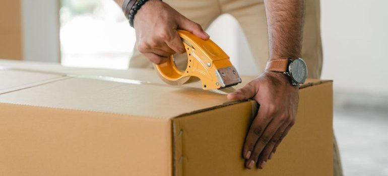 A man taping a box and waiting for movers and packers CT