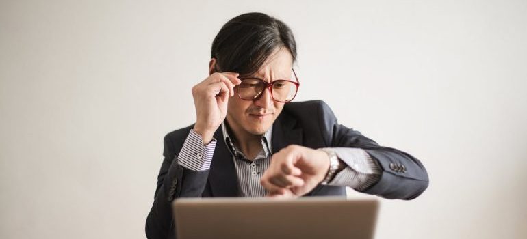 A man looking at his watch and thinking about hiring last minute movers