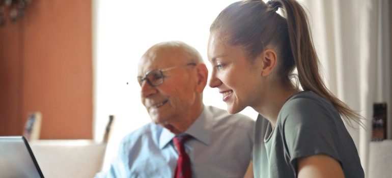 A young woman helping a senior man to use the internet