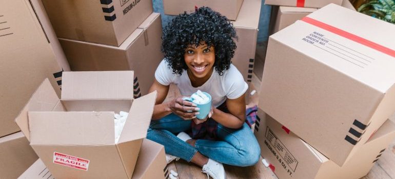 A woman sitting among boxes and waiting for her long distance movers Connecticut offers